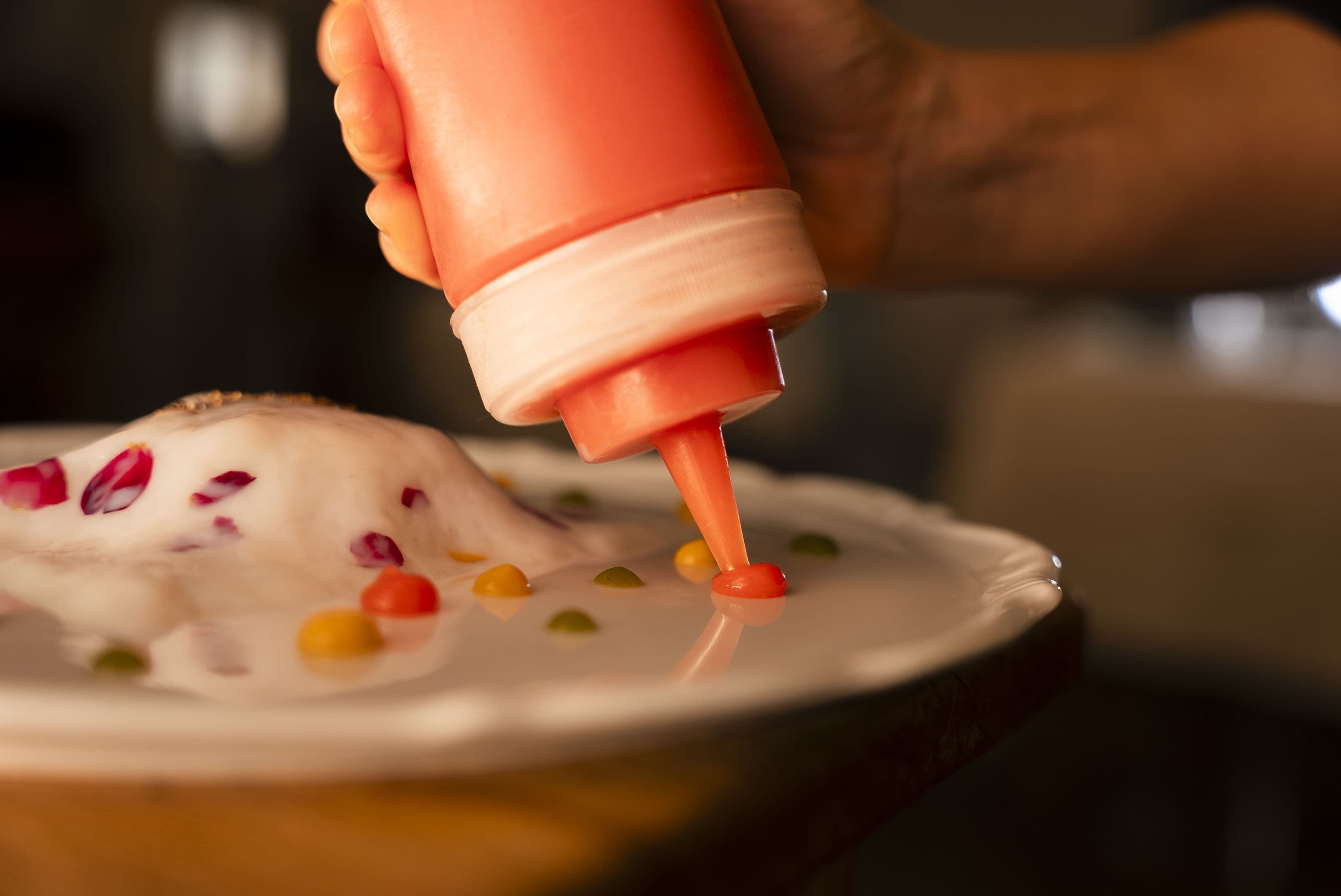A hand finishing a dish in the kitchen